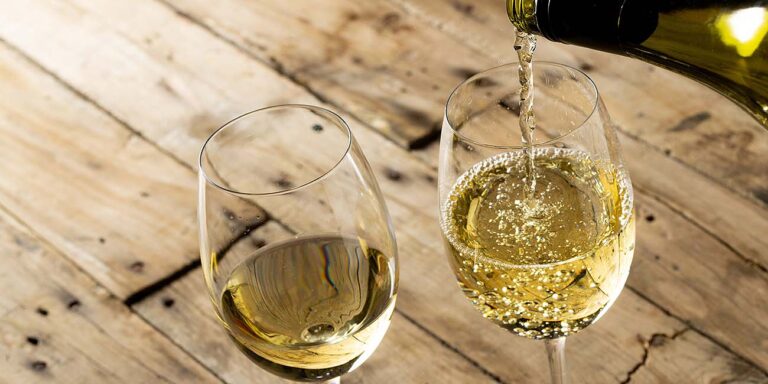 white wine being poured into two wine glasses